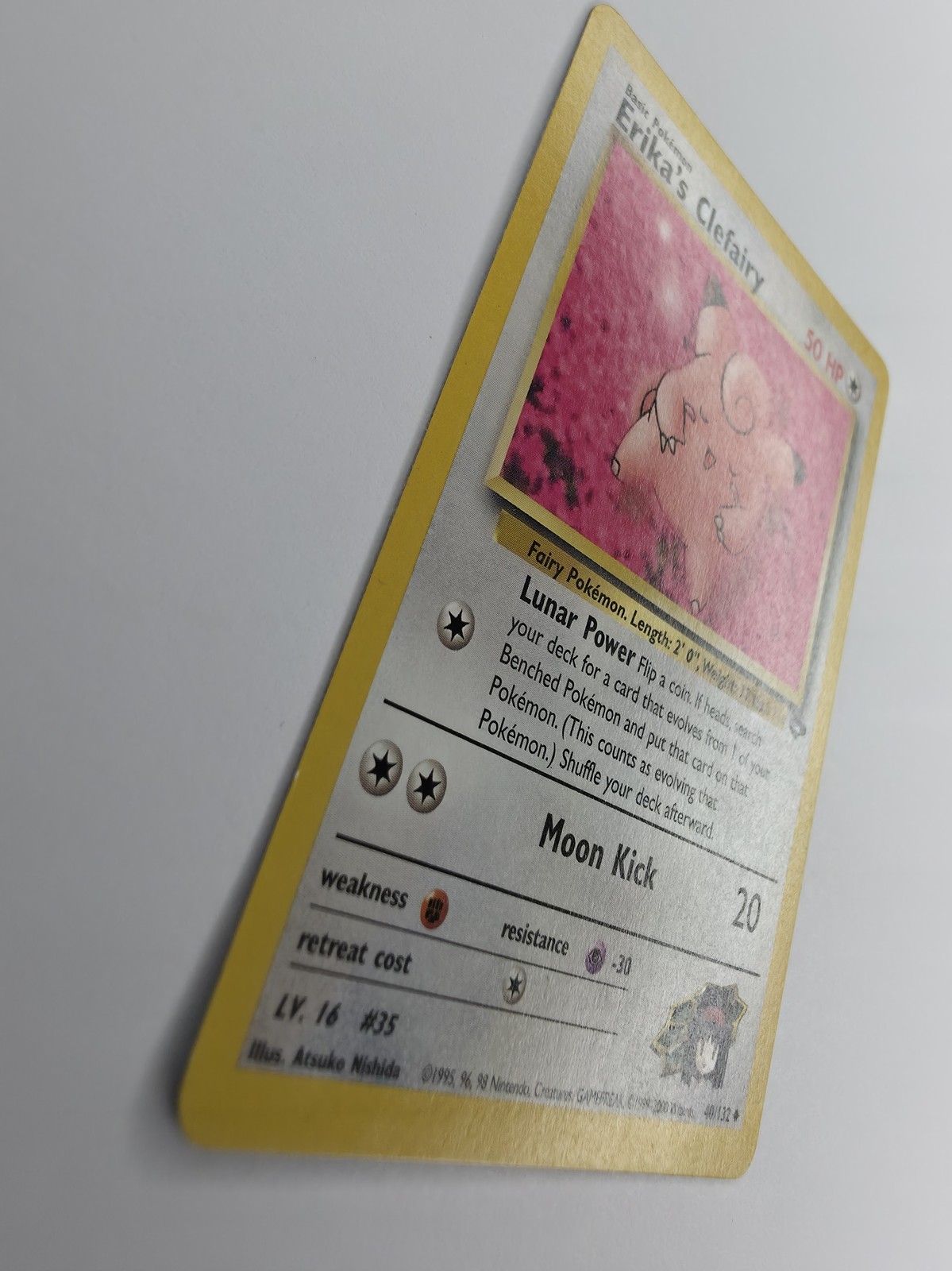 Erika's Clefairy, front gloss across art and text box under raking light, tilted